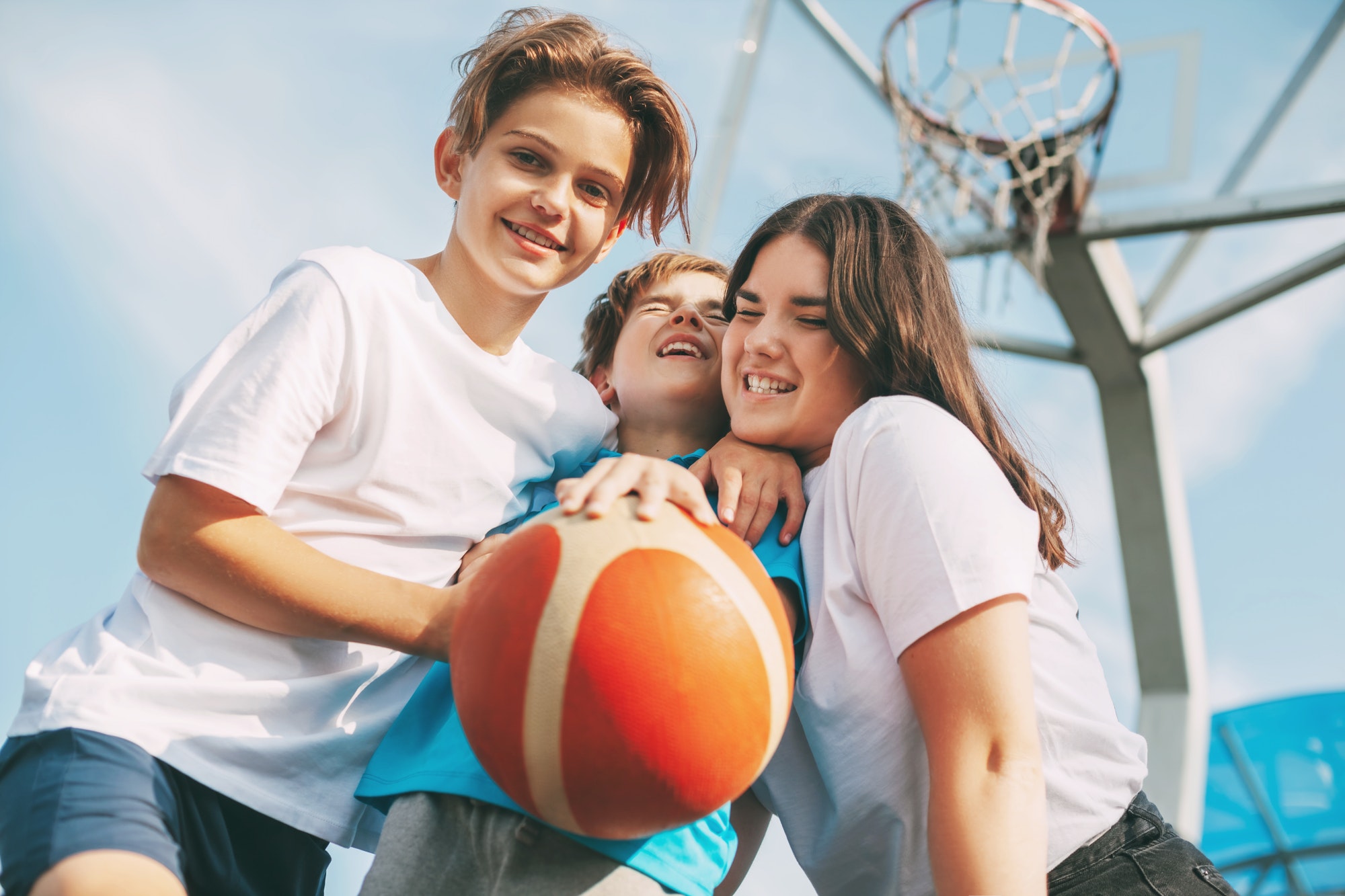 Happy friends are standing hugging on the basketball court and having fun . Sports, games