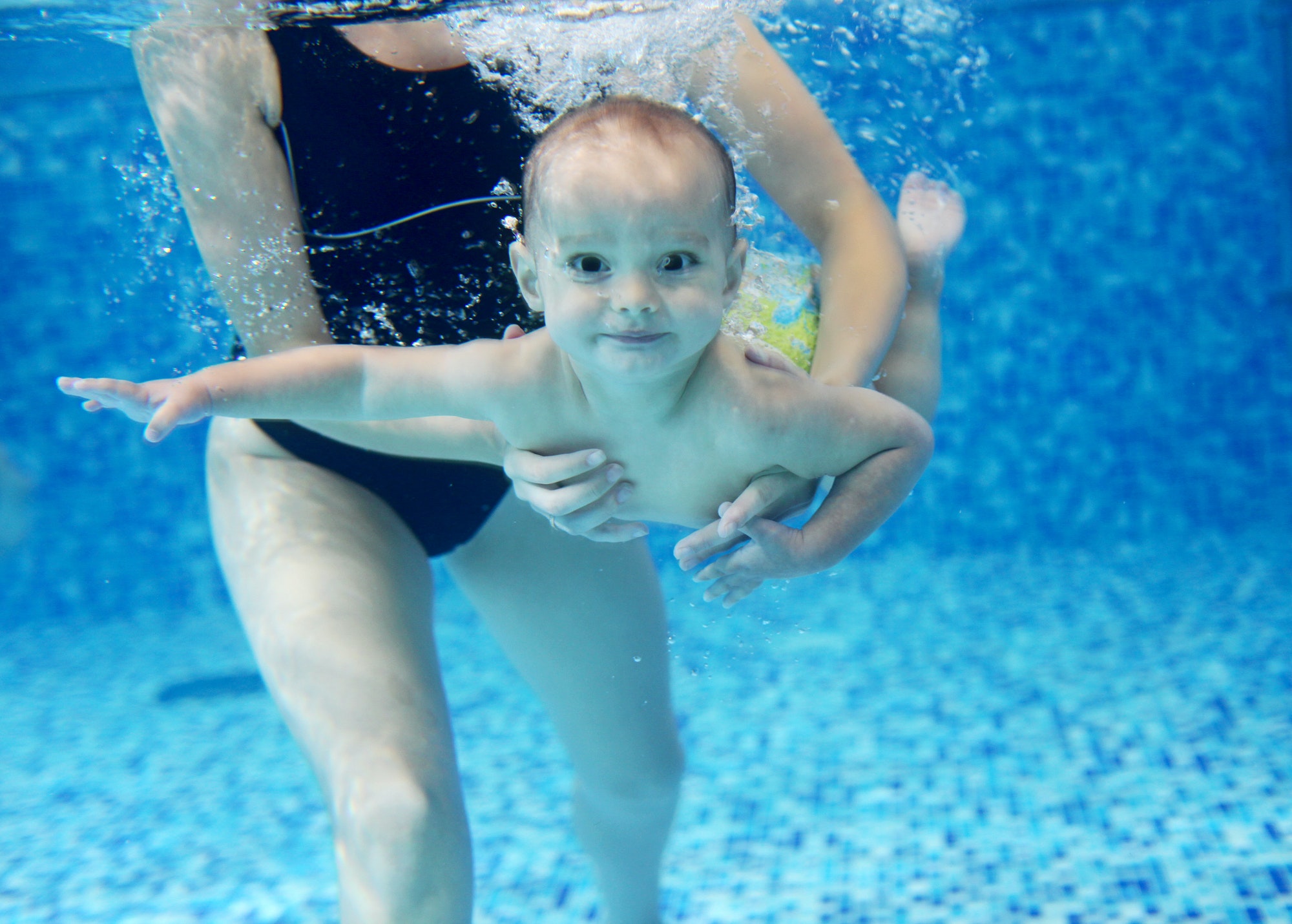 Little boy learning to swim in a swimming pool