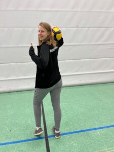 Trainerin Sophie Schröder steht mit einem Volleyball in der Halle.