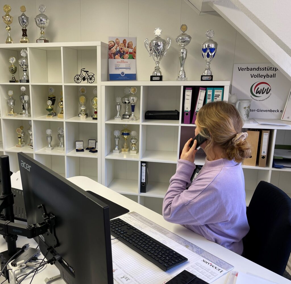 Eine Mitarbeiterin der Geschäftsstelle sitzt an ihrem Schreibtisch und telefoniert.