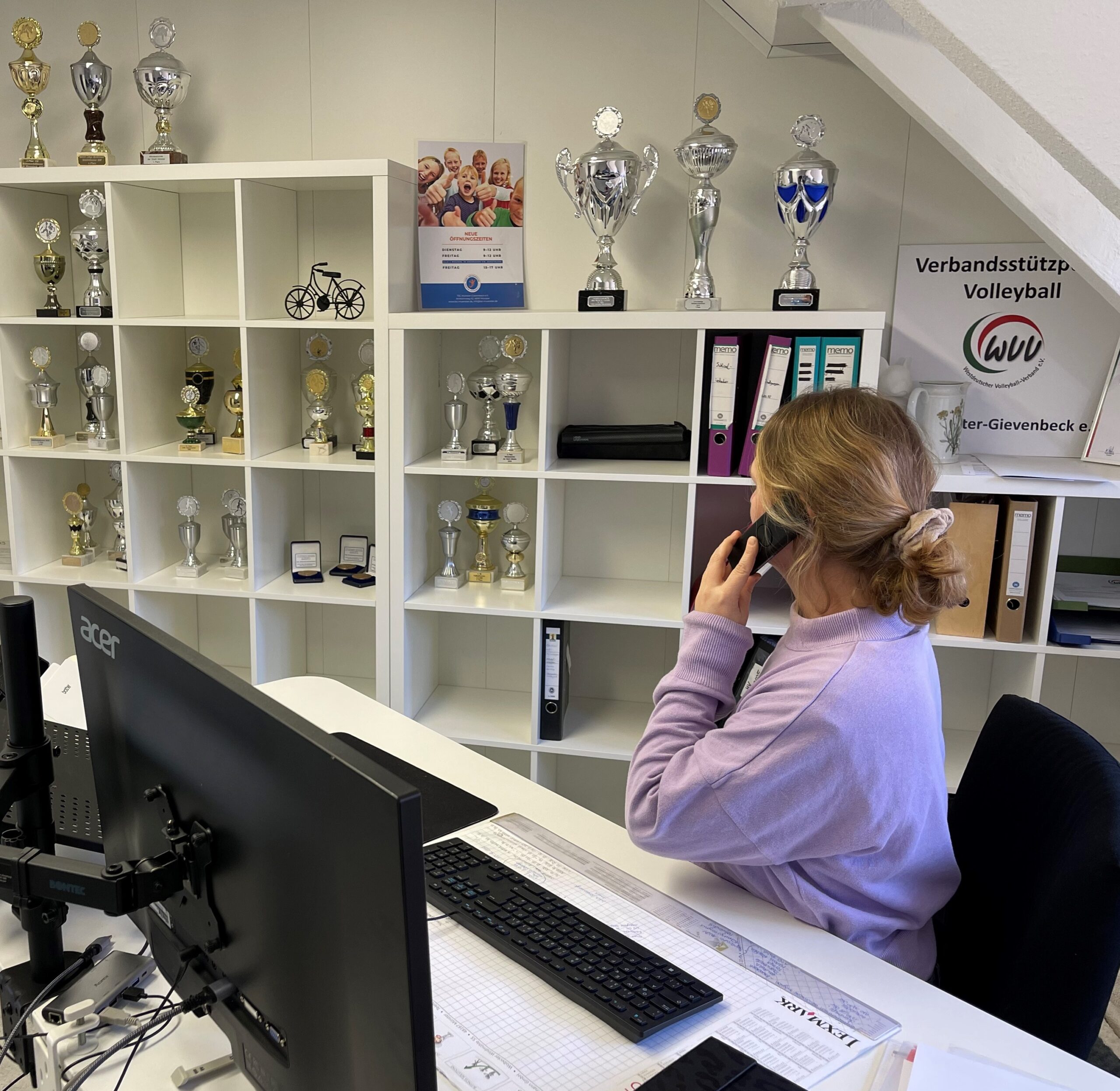 Eine Mitarbeiterin der Geschäftsstelle sitzt an ihrem Schreibtisch und telefoniert.